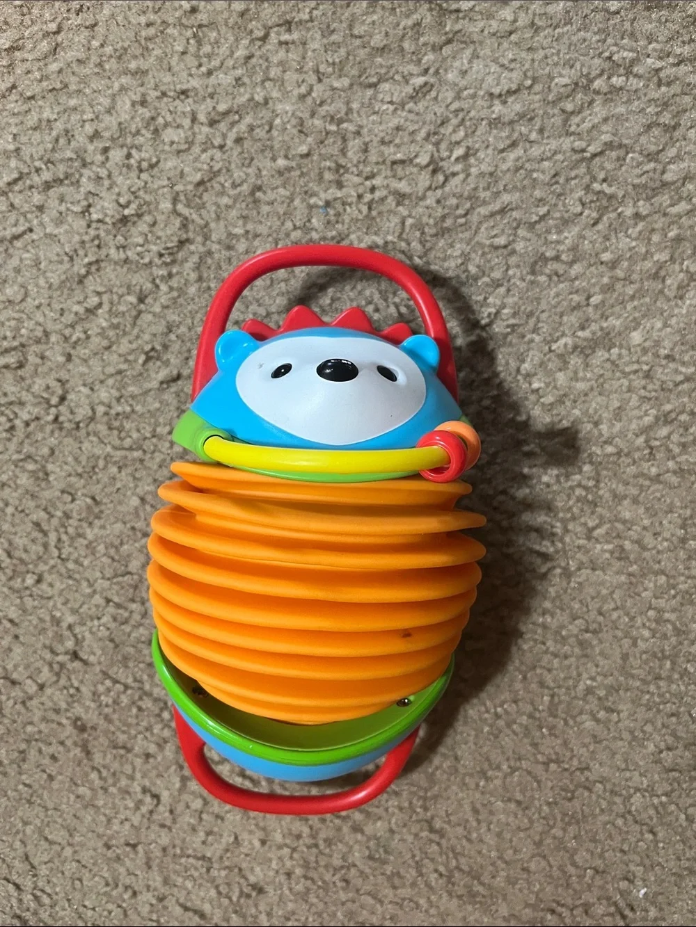 Skip Hop Orange Accordion Hedgehog Toy with Blue Face and Red Handles